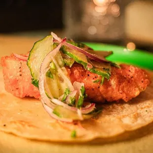 a taco with meat and vegetables on a green plate