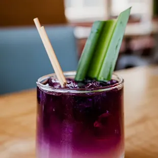a purple drink with a cucumber garnish