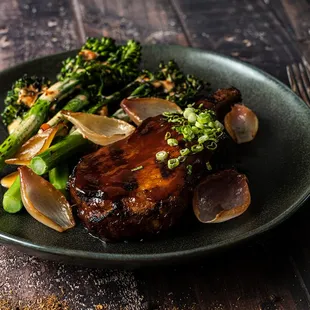 a plate of meat, broccoli, and onions