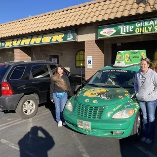 two women standing in front of a car