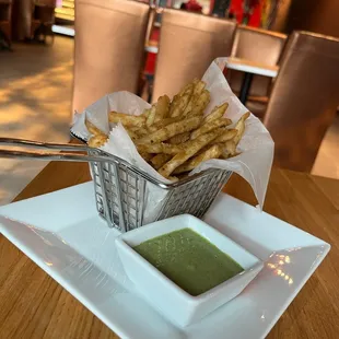 a basket of french fries with dipping sauce