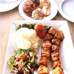 This image showcases a beautifully presented Turkish chicken kebab platter. The dish features succulent, perfectly grilled chicken skewers s