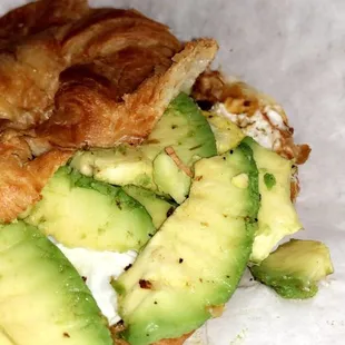 a croissant sandwich with avocado