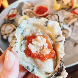 a person holding a half shell of oyster