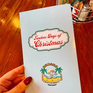 a hand holding a christmas menu