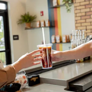 a woman handing a drink to a customer