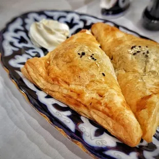 Meat Pirozhki - baked pies made with filo dough, stuffed with ground beef and onions seasoned with spices, served with sour cream.