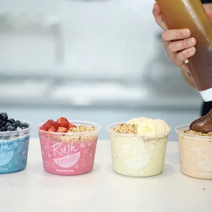 a person pouring a liquid into a bowl of yogurt