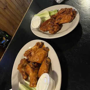 two plates of chicken wings and celery