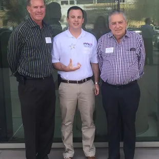three men standing in front of a glass building