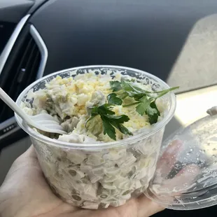 a hand holding a plastic bowl of food