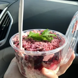 a hand holding a plastic container filled with food