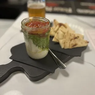 a small glass jar of sauce with a spoon and crackers