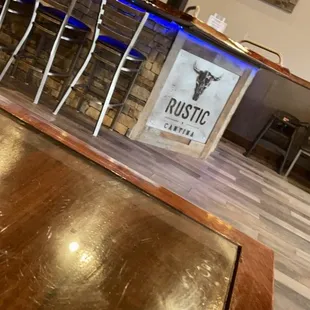 a bar with stools and televisions