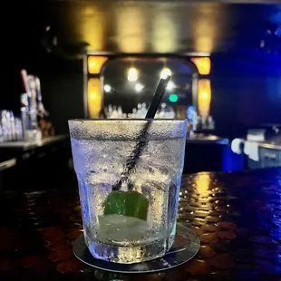 a glass of water with a straw and a mint leaf in it