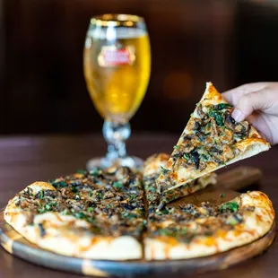 a person taking a slice of pizza