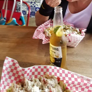 a woman sitting at a table with food and a bottle of beer