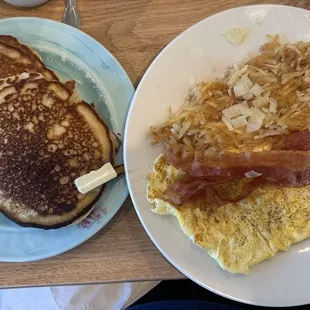 Deluxe breakfast with scrambled eggs, hashbrowns with onion, bacon, and blueberry pancakes
