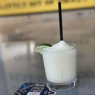 a drink in a glass with a straw and a lime garnish