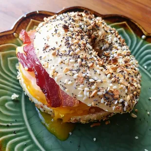 a bagel with bacon, cheese, and mustard