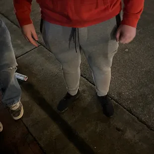 a man in a red hoodie standing on a sidewalk