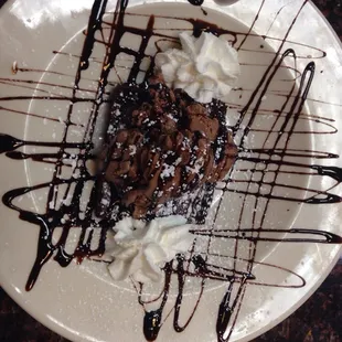 Warm brownie topped with whipped cream, ice cream, and chocolate sauce.