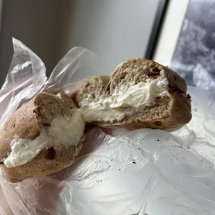 a person holding a bagel with a bite taken out of it