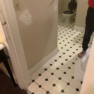 Broken floor tiles and towel rack on the wall