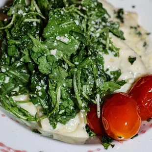 a plate of food with spinach and tomatoes