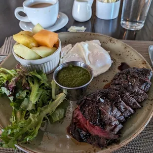 Steak and eggs with mixed greens, pesto sauce and fruit