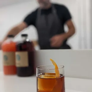 a man behind a counter with a glass of whiskey