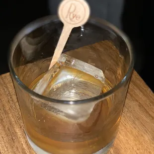 a glass of whiskey with a wooden spoon in it