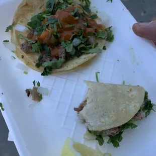 Half eaten carnitas taco and a carne assada taco with red sauce poured on it. Mmmm!!!