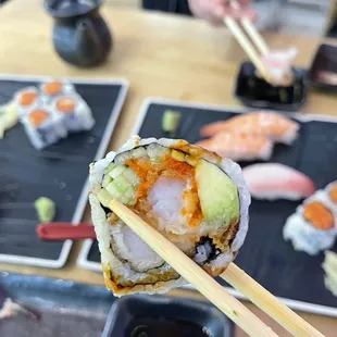 a person holding chopsticks over a sushi