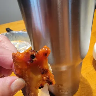 a hand holding a piece of pizza
