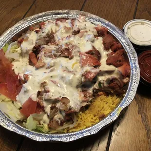 Halal chicken over rice with extra white sauce and hot sauce.
