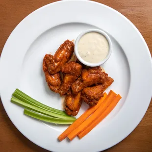 a plate of chicken wings, carrots and celery