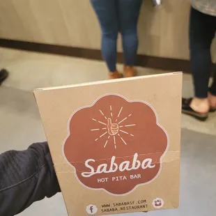 a person holding a box of pizza