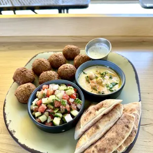 Falafel plate with two sides, a sauce and pita bread.