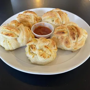 a plate of bread rolls with dipping sauce