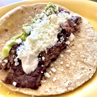 a beef taco on a yellow plate