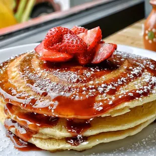 a stack of pancakes with syrup and strawberries