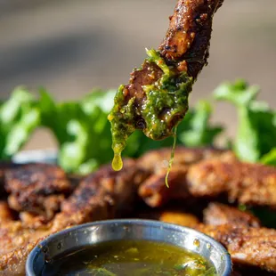 a piece of meat being dipped with sauce