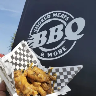 a hand holding a basket of chicken wings