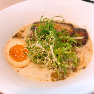 a bowl of ramen with an egg and sprouts