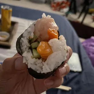 a hand holding a piece of sushi