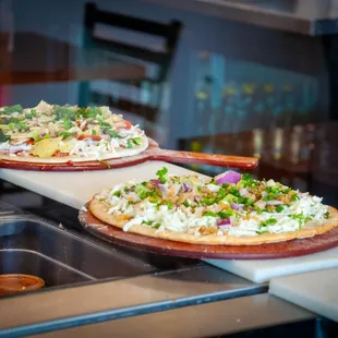 two uncooked pizzas
