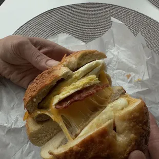 Breakfast bagel with melted cheddar, sausage, bacon in a Parmesan bagel