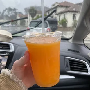 a hand holding a cup of orange juice