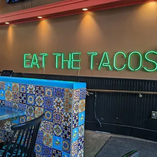 a neon sign that says eat the tacos